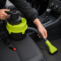 Handheld car vacuum cleaner being used to clean car seat with flexible hose and brush nozzle